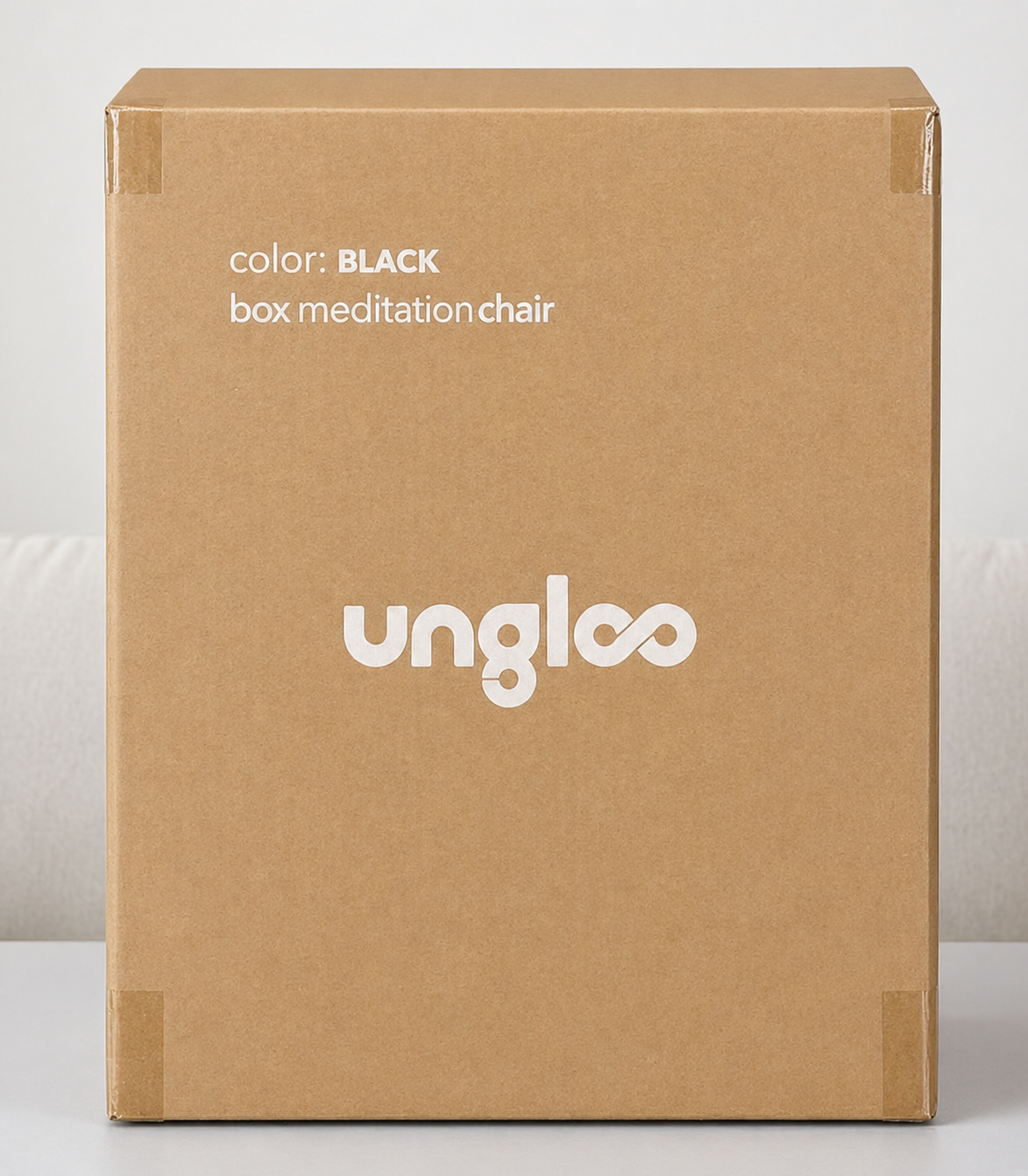 Black Ungloo Box portable meditation chair with back and hip support, shown in cardboard packaging for easy transport.