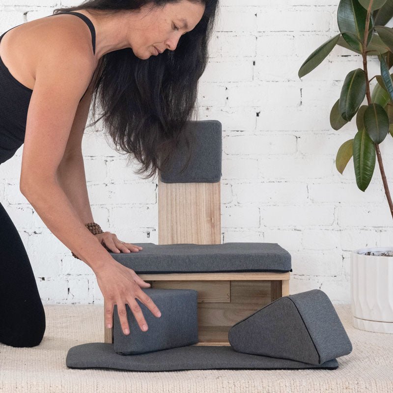 Natural-colored Ungloo Box portable meditation chair with back and hip support, shown with props in a relaxed setting.